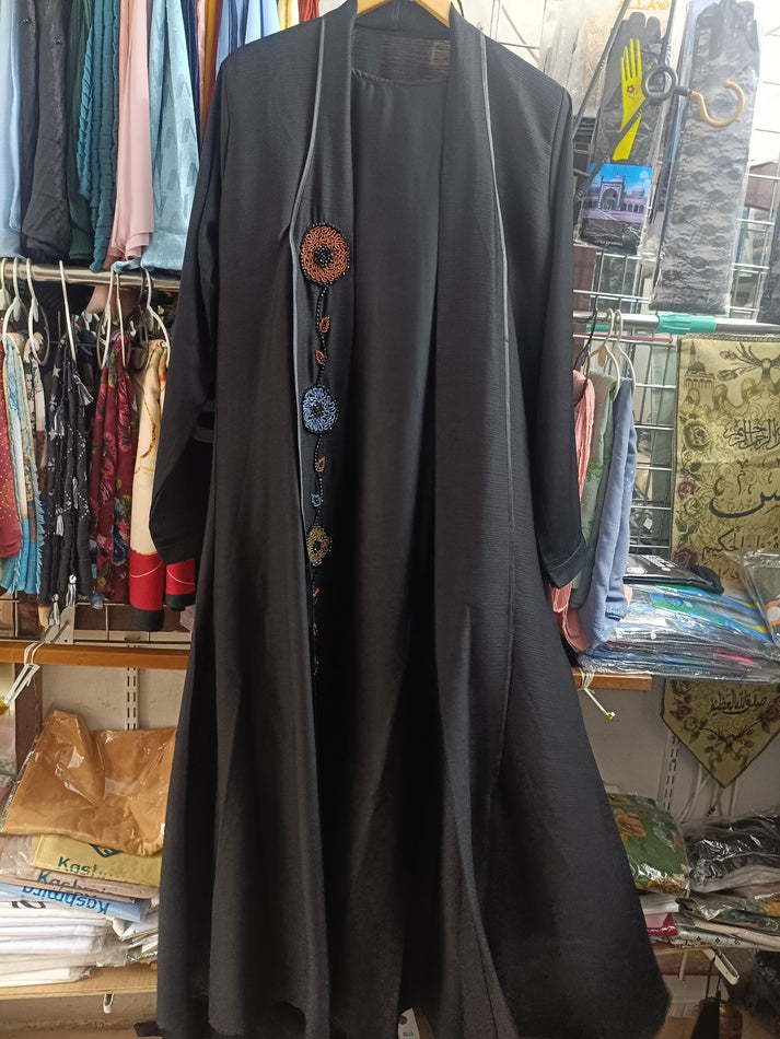 Woman wearing black open front abaya with multicolor circular embroidered motifs and black hijab