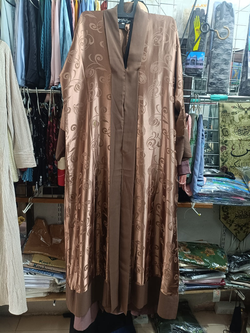 Woman wearing bronze jacquard open abaya with brown trim and hijab