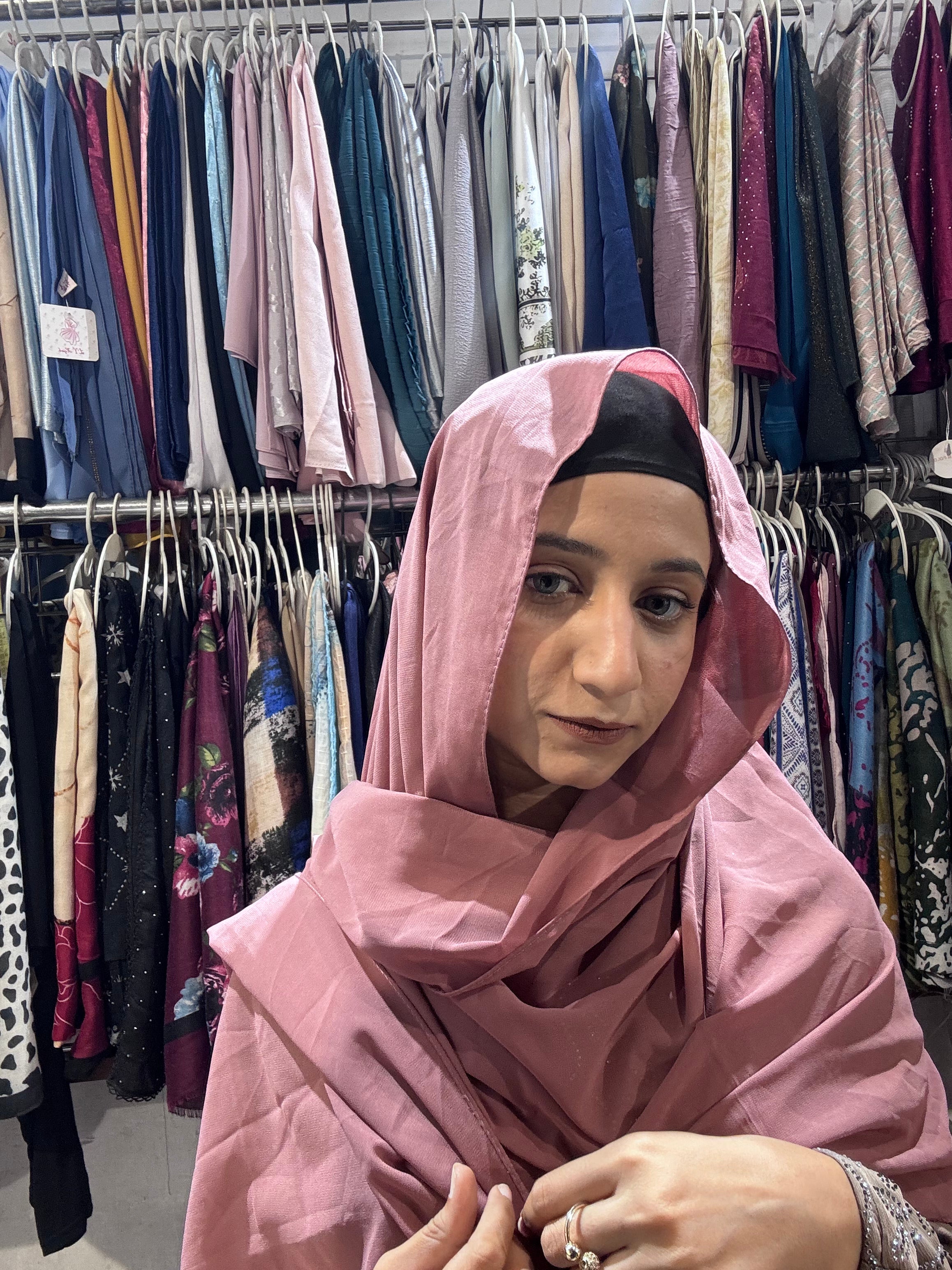 Woman wearing dusty rose pink hijab scarf in clothing store