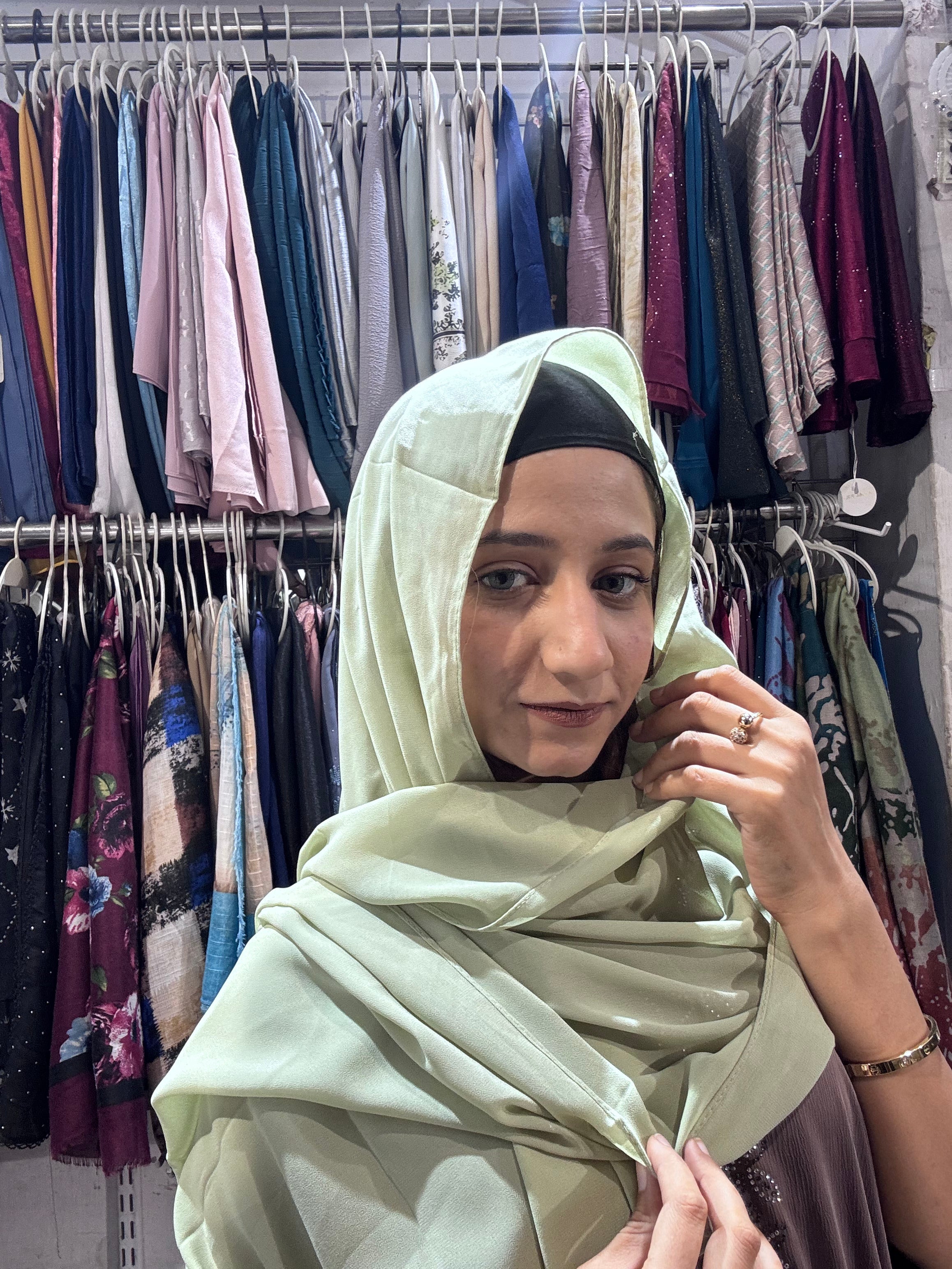 Woman draping mint green premium chiffon hijab scarf in clothing store