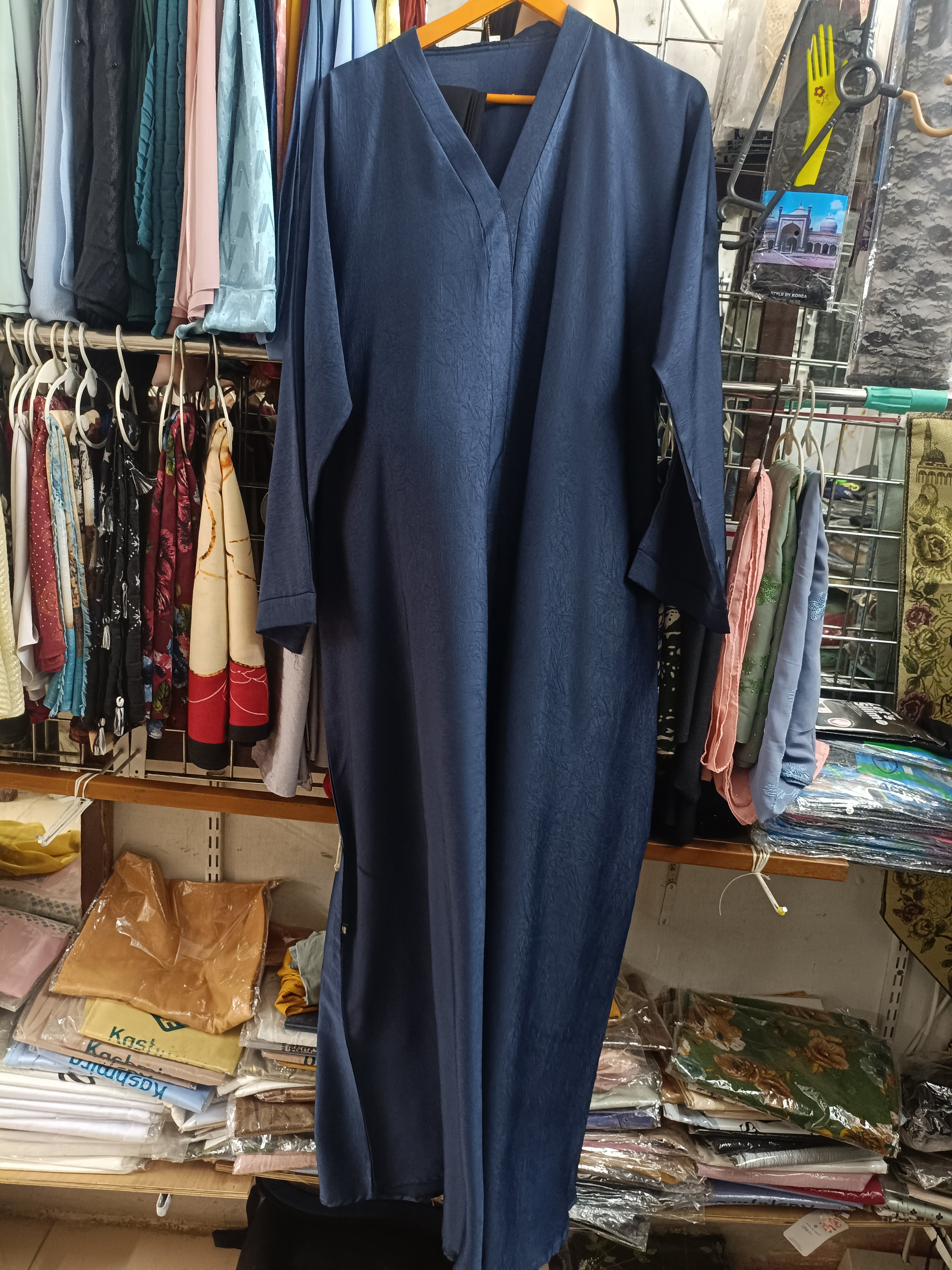 Navy blue jacquard texture closed abaya with V-neck full length view on hanger in store