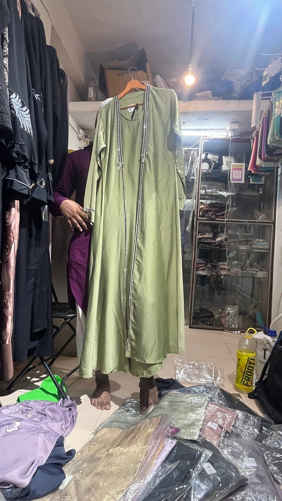 Woman wearing pistachio green abaya with silver bead trim, bow detail and matching hijab