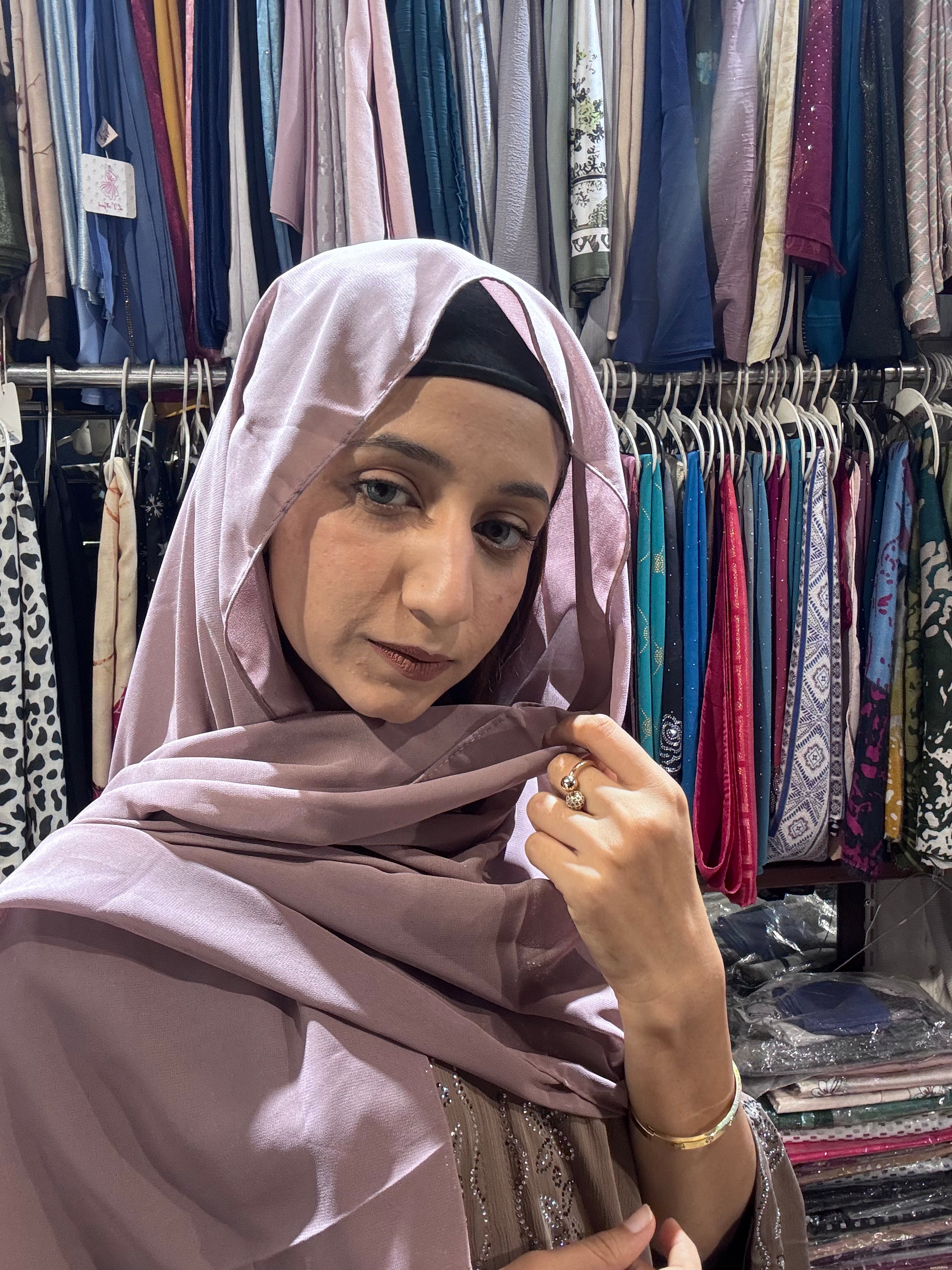Woman wearing mauve pink premium chiffon hijab scarf in clothing store