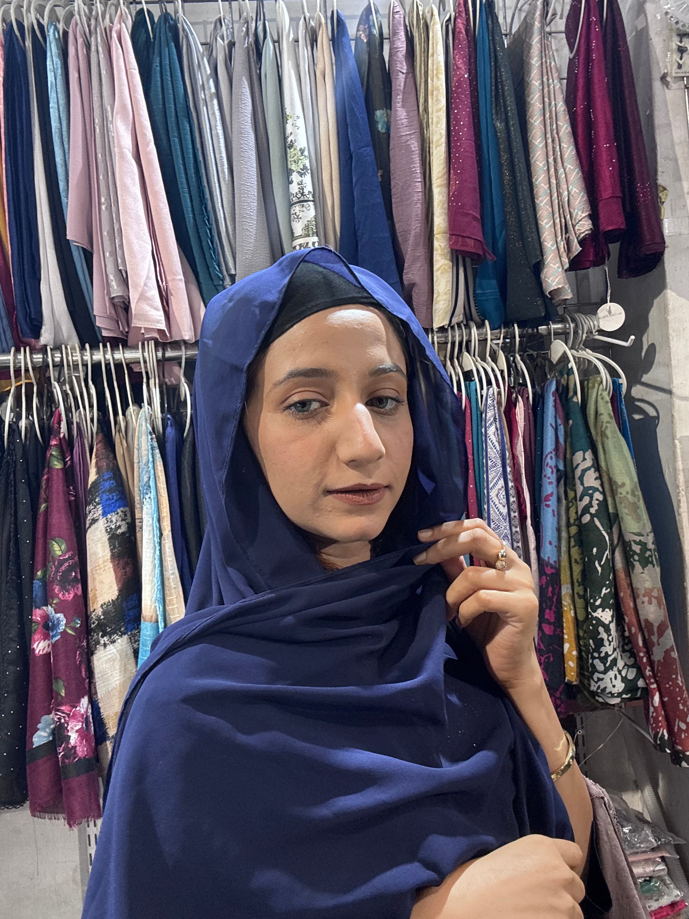 Woman wearing navy blue premium chiffon hijab scarf in clothing store