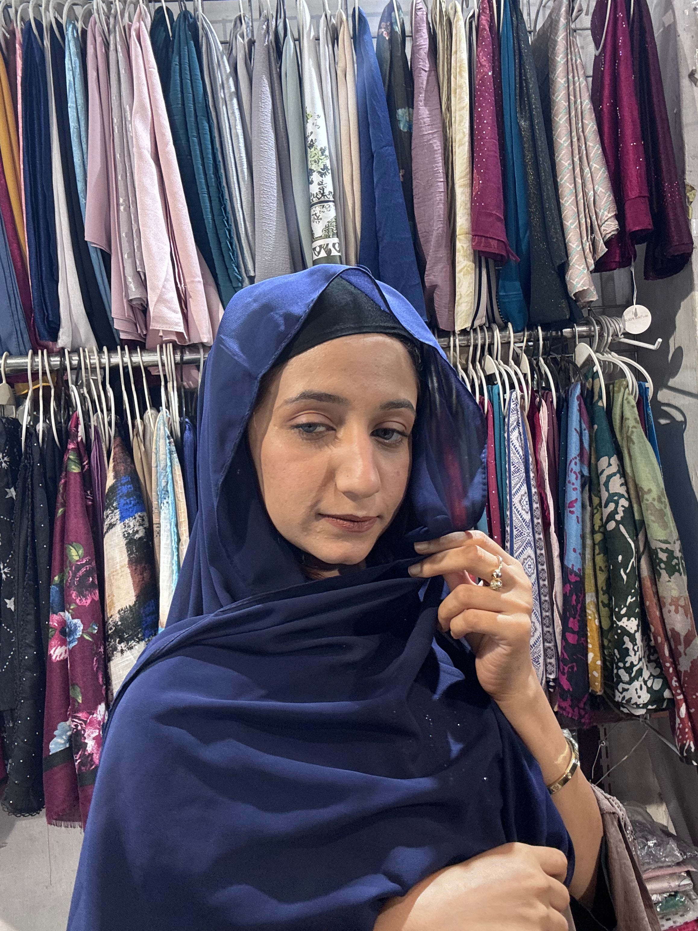 Woman styling navy blue premium chiffon hijab in boutique store