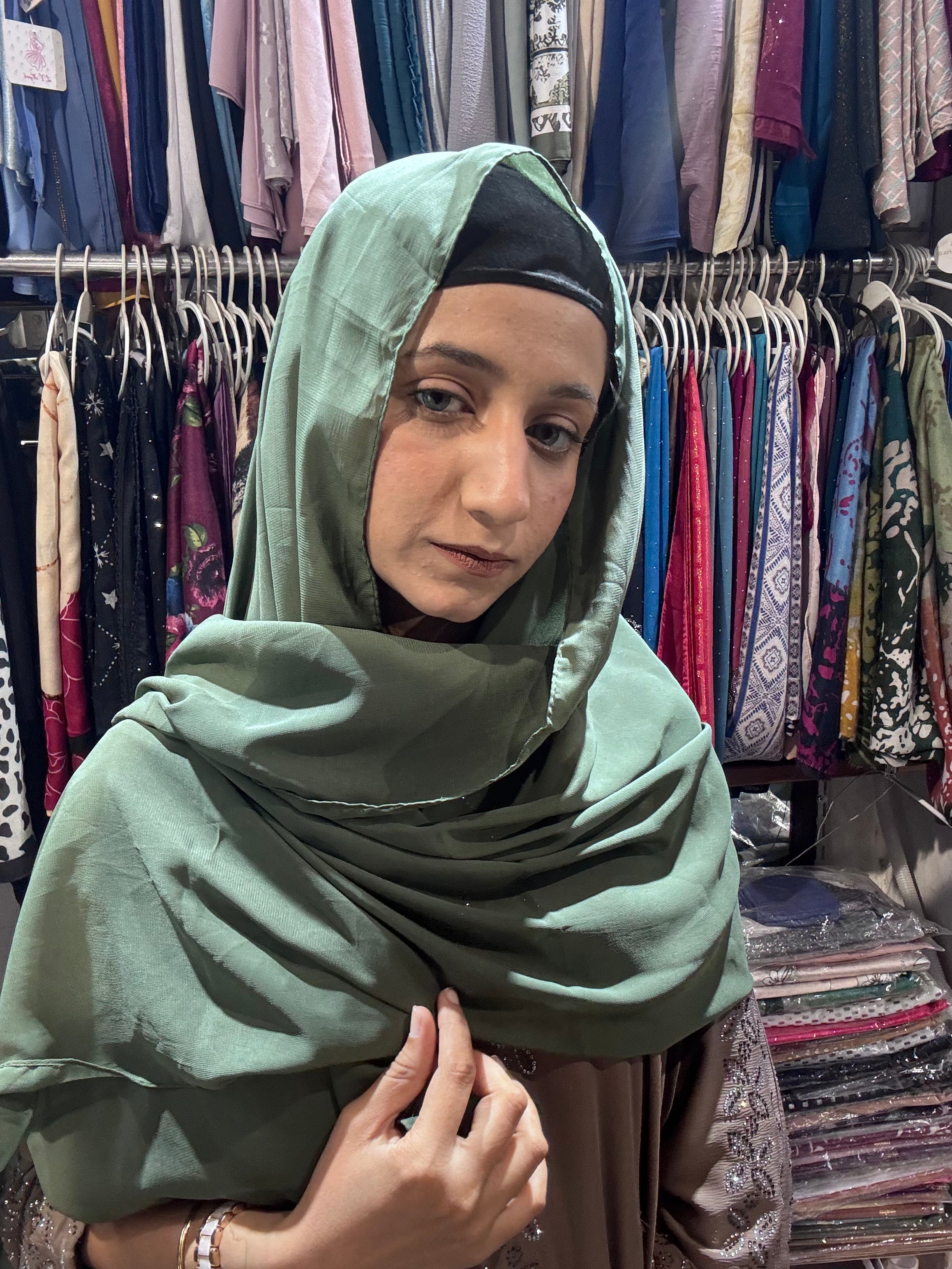 Woman wearing olive green premium chiffon hijab scarf in clothing store