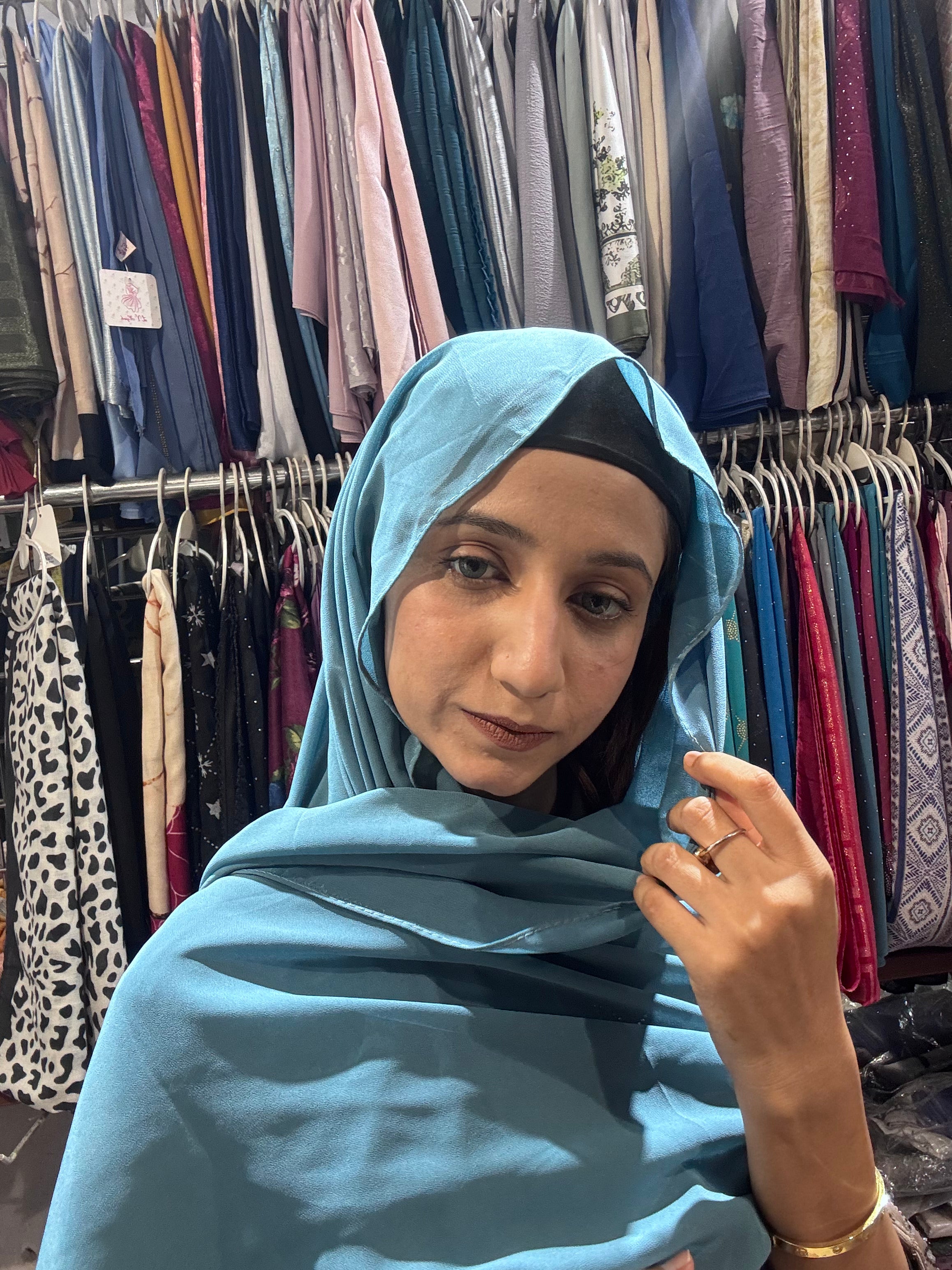 Woman styling sky blue premium chiffon hijab scarf in boutique store