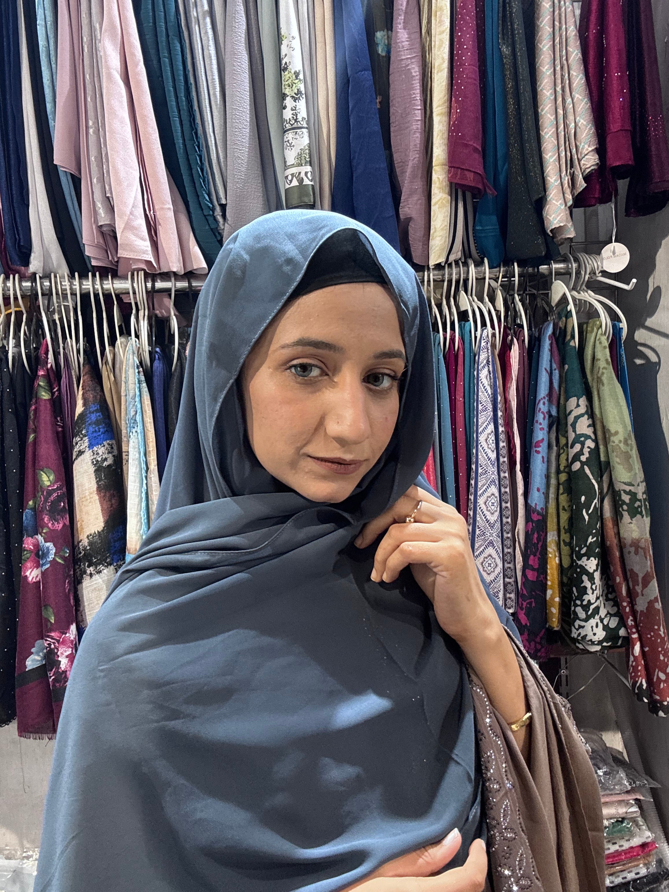 Woman wearing steel blue premium chiffon hijab scarf in clothing store