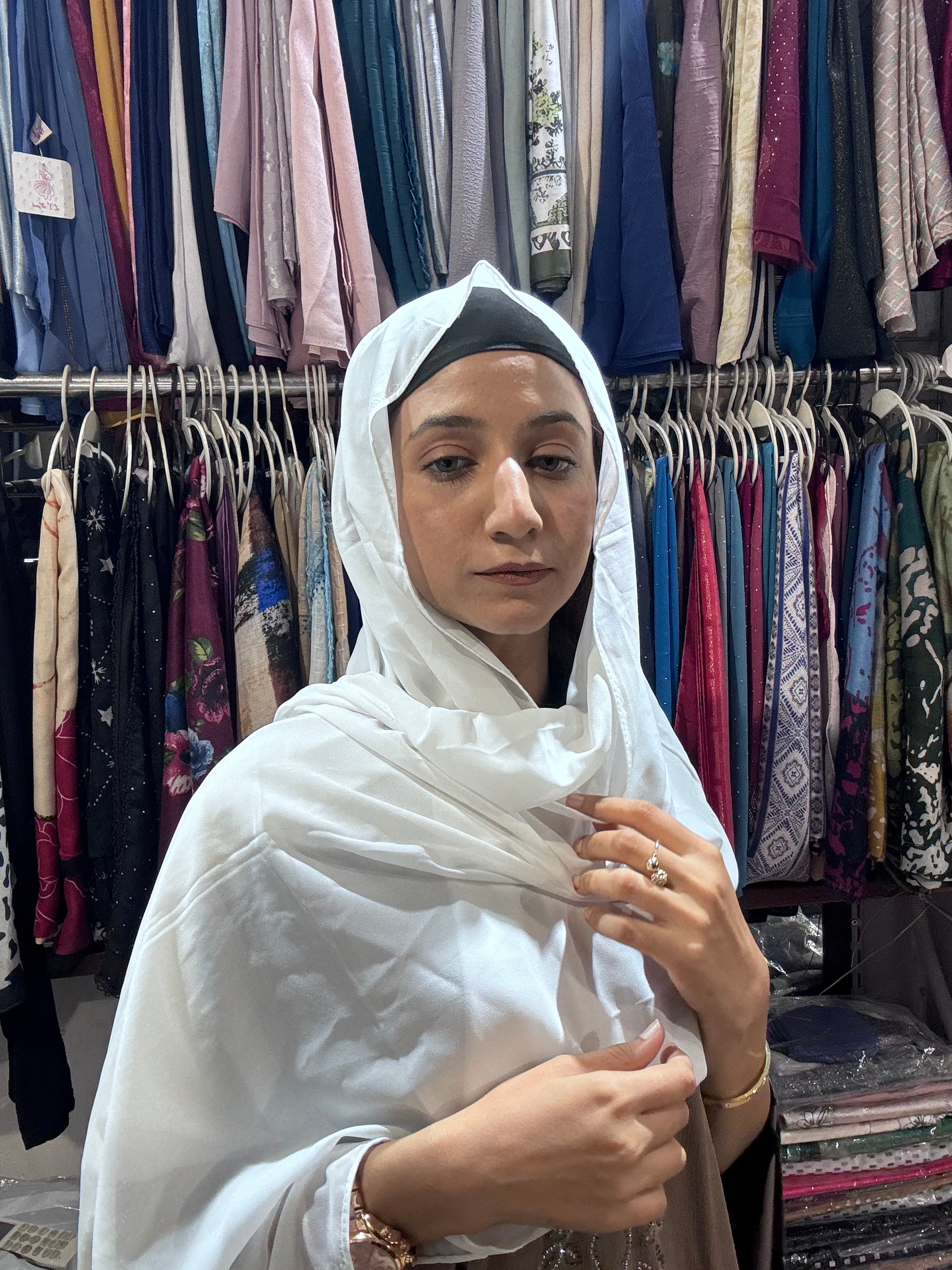 Woman styling white premium chiffon hijab scarf in boutique store